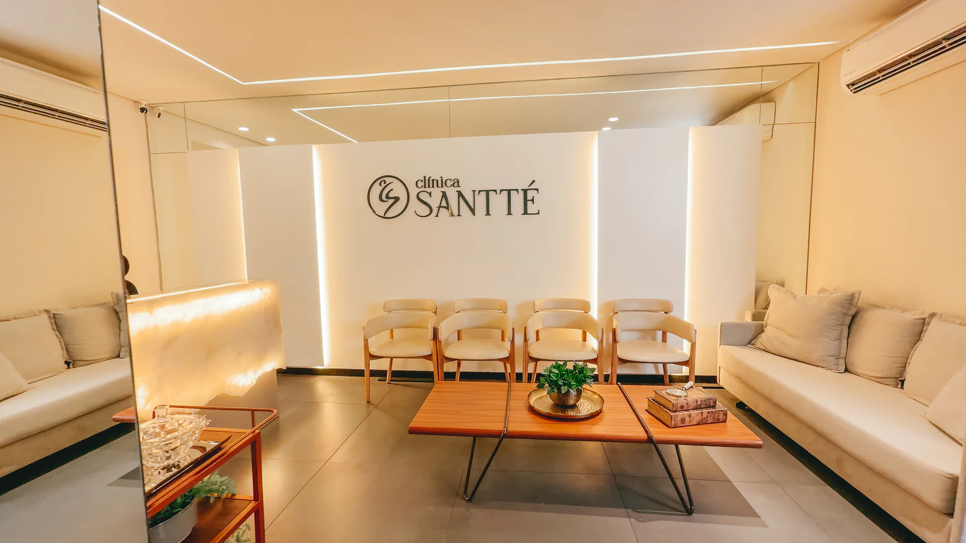 Sala de espera da Clínica Santté, com sofás, poltronas e a marca da clínica na parede
